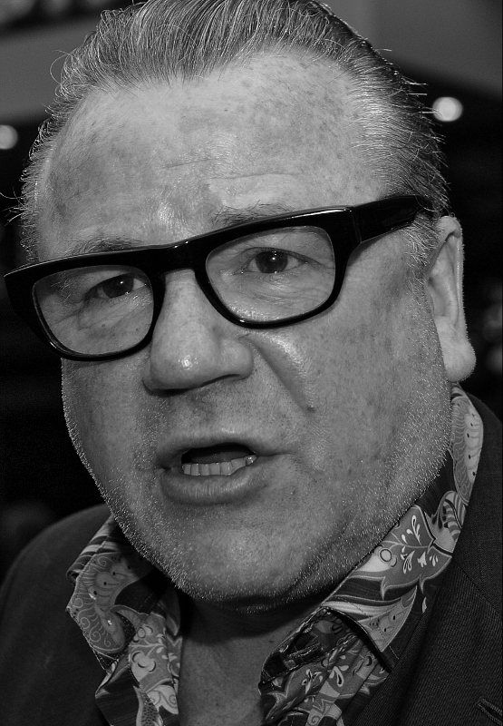 man wearing glasses standing in black and white po