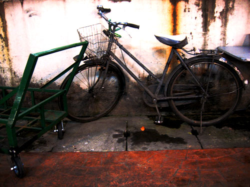 an old bicycle sitting next to a green cart