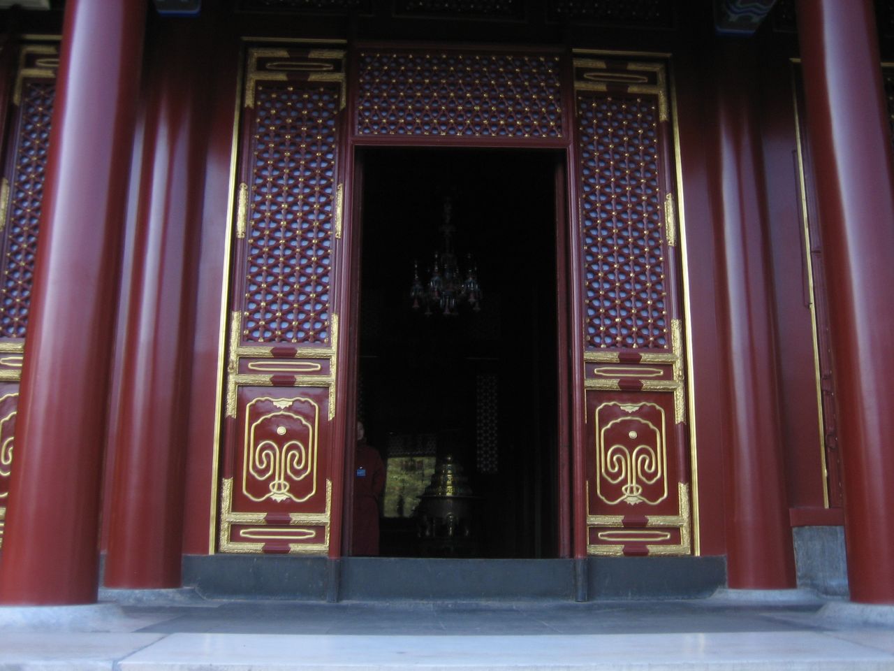 the doors of this oriental building are decorated with gold and red columns
