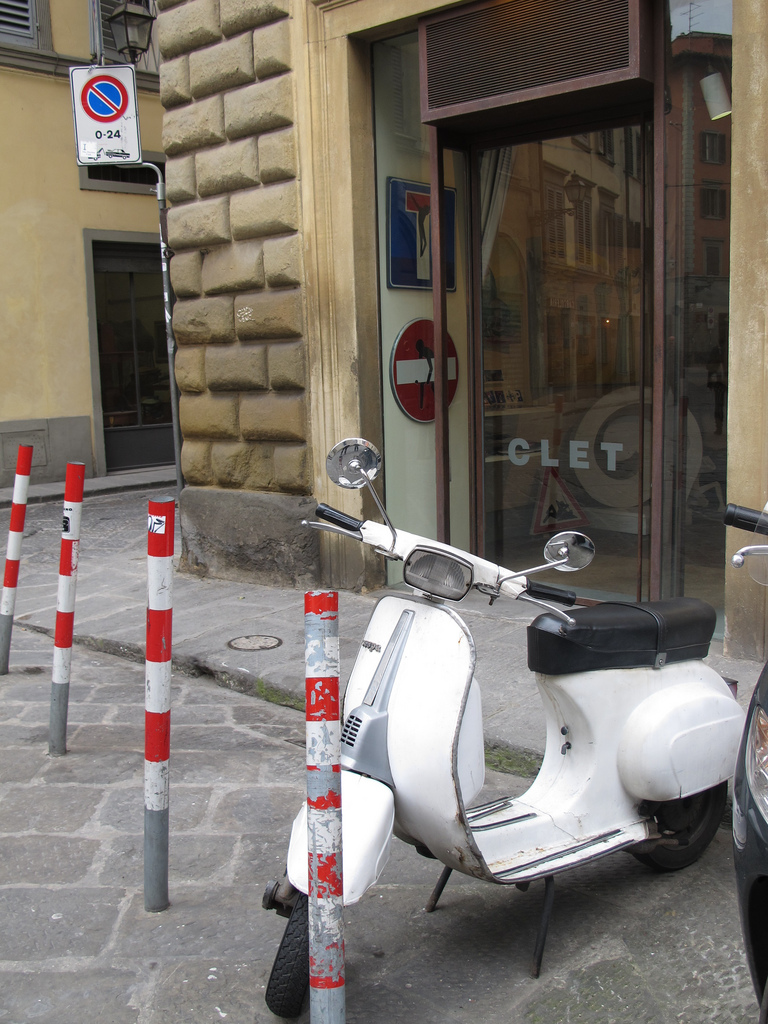 a scooter parked next to two cones, a door and other buildings