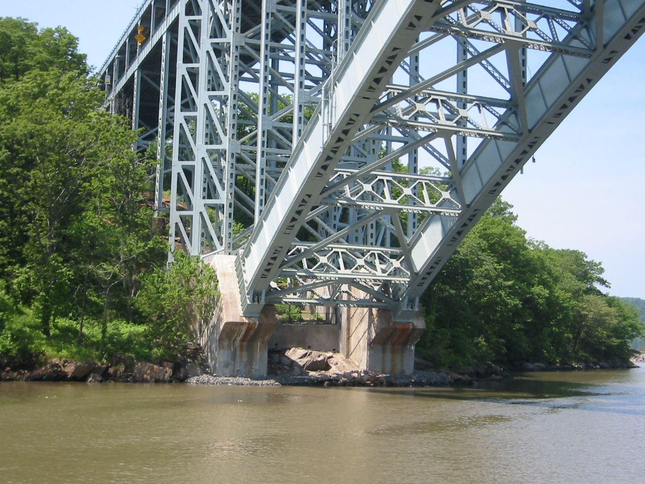 a bridge spanning a wide river into a wooded area