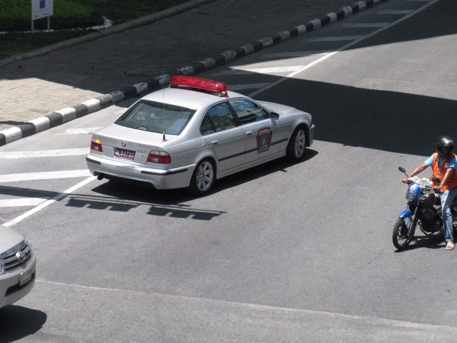 a motorcycle rider and police car are on the street