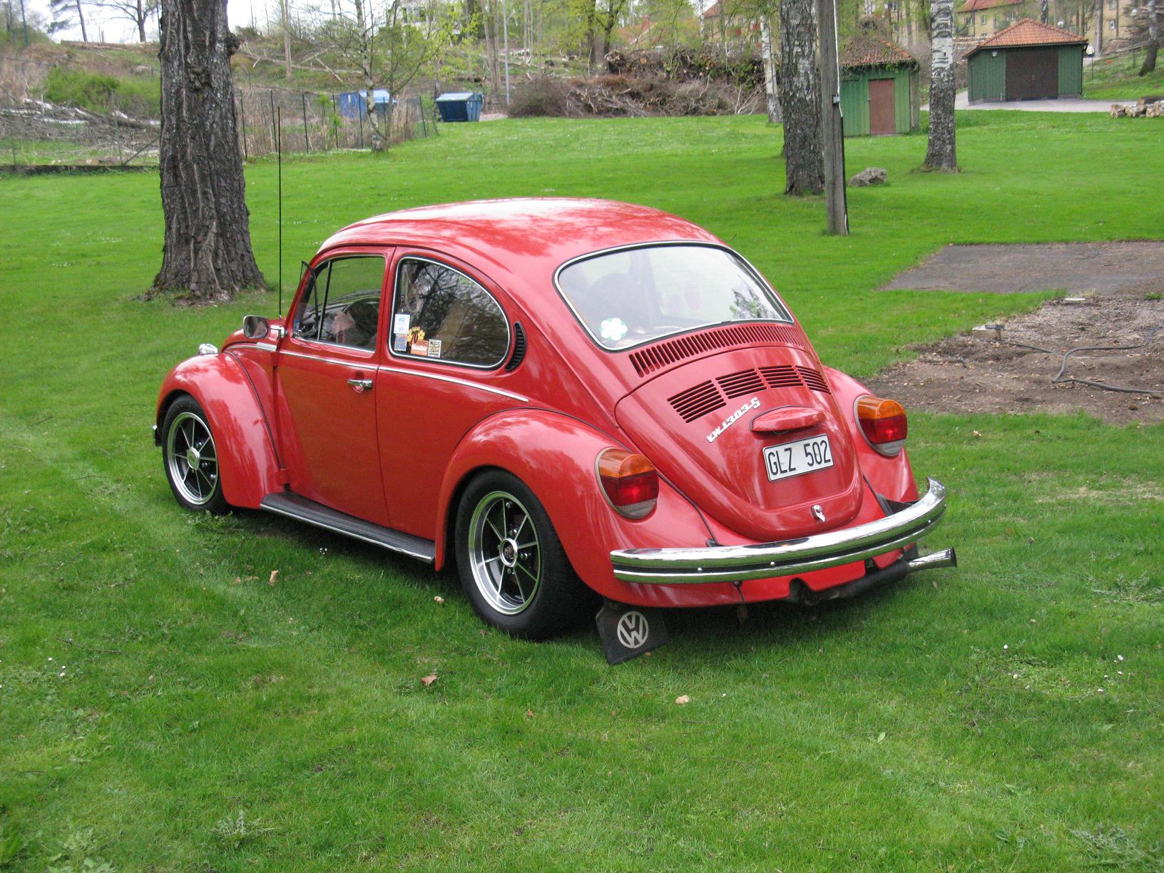 an old red vw bug on the grass