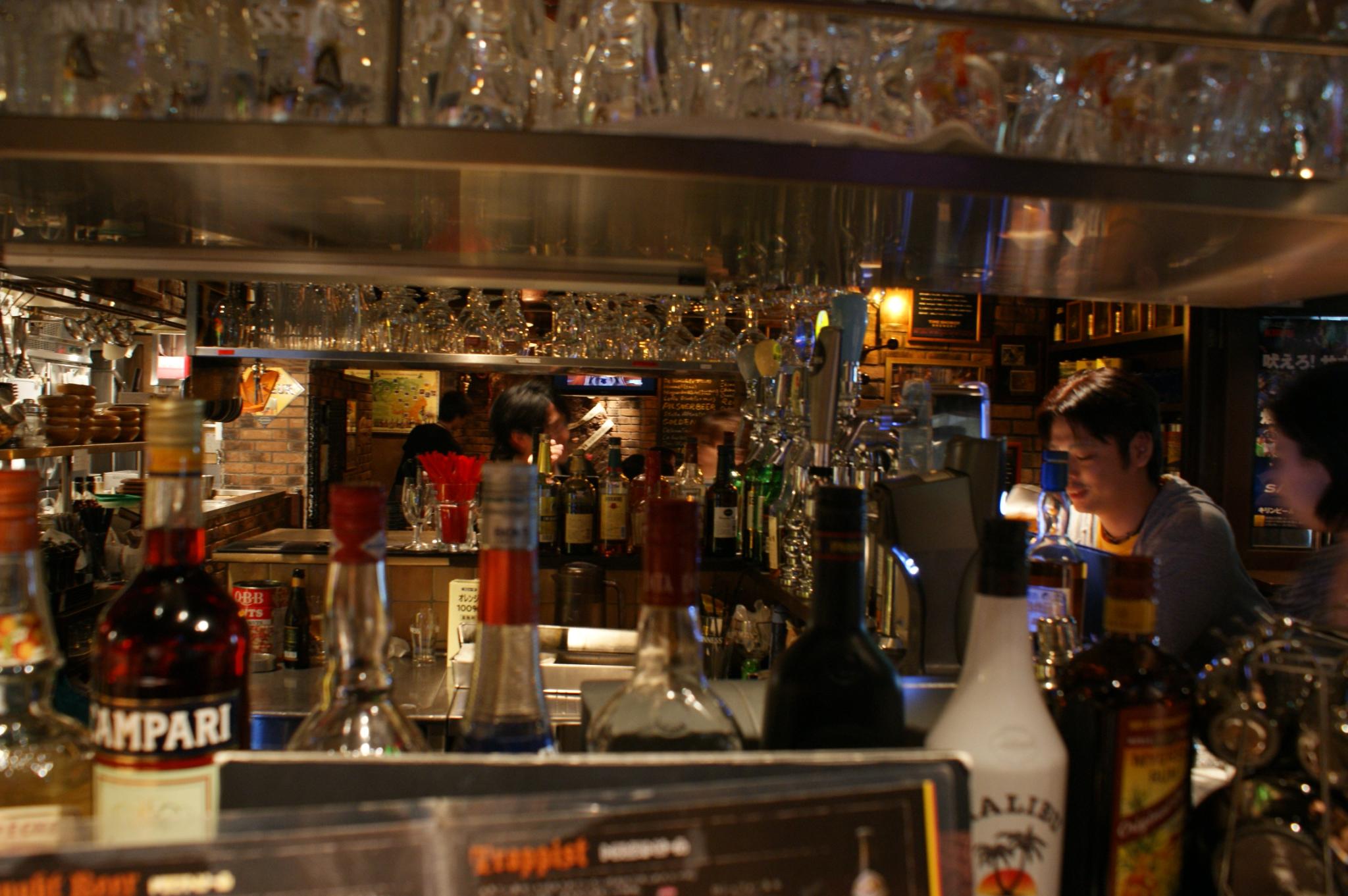 a bar with various bottles of alcohol behind a woman