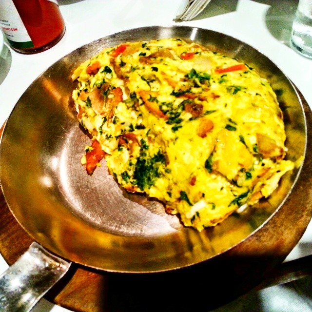 an omelette with vegetable and chicken in a ss bowl on a table