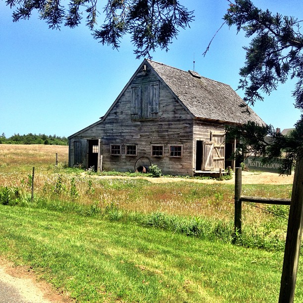 an old barn is sitting near the road