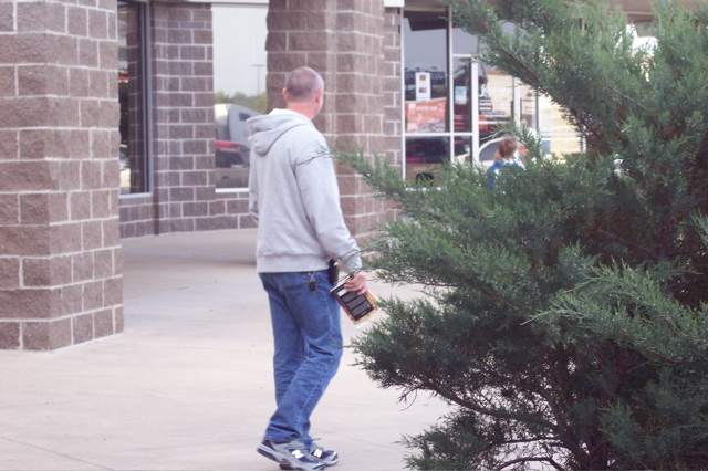 the man is walking past a very large plant