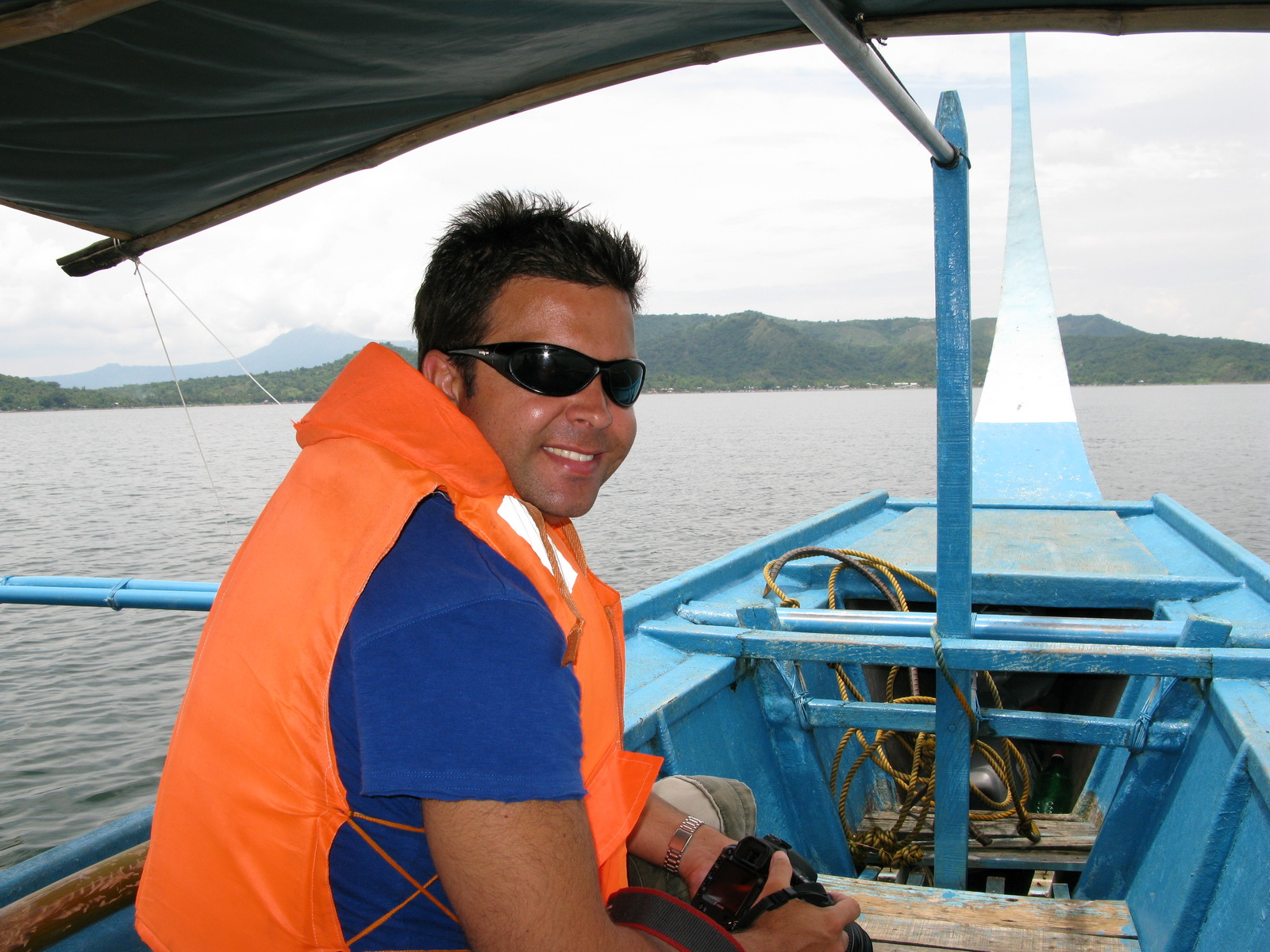 a man in sunglasses sits on the front of a blue boat