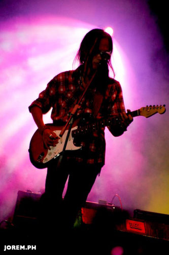 a man standing on stage playing guitar at a concert