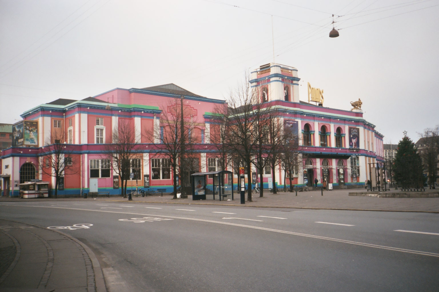 a street corner next to a building painted pink and blue