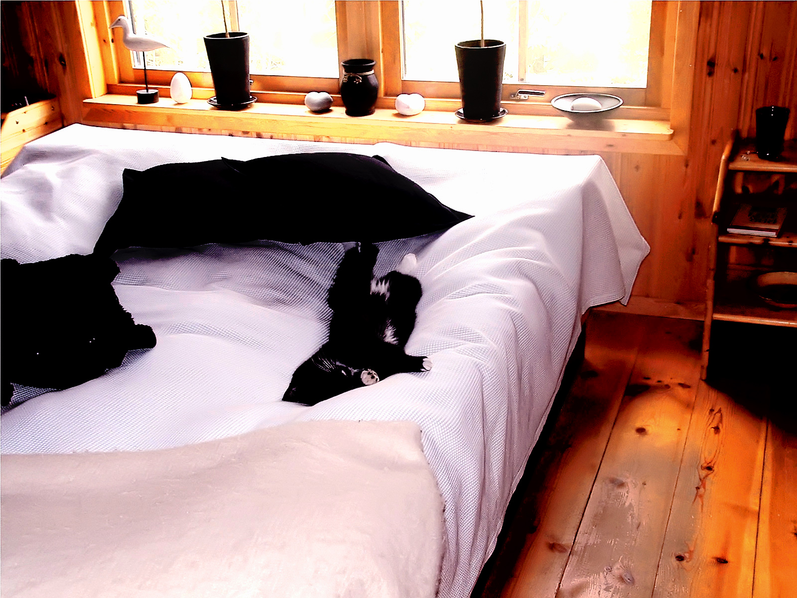 a bed with white sheets and some black boots on top