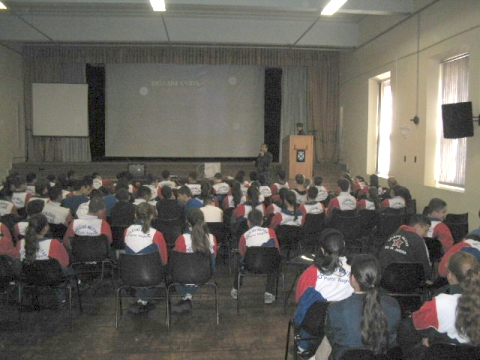 a room full of people sitting in chairs with large screens and a projector screen