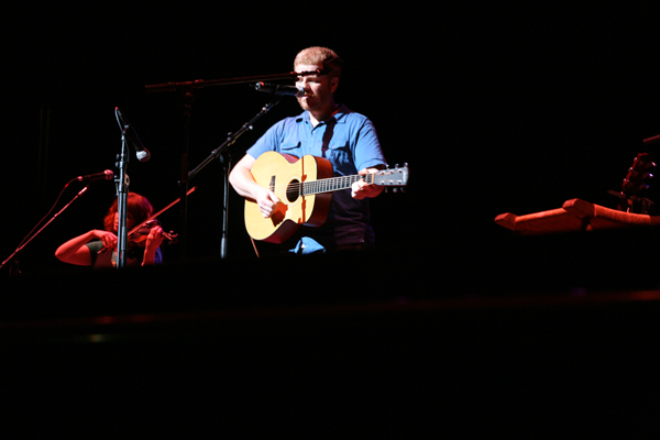 a man in blue shirt holding a guitar