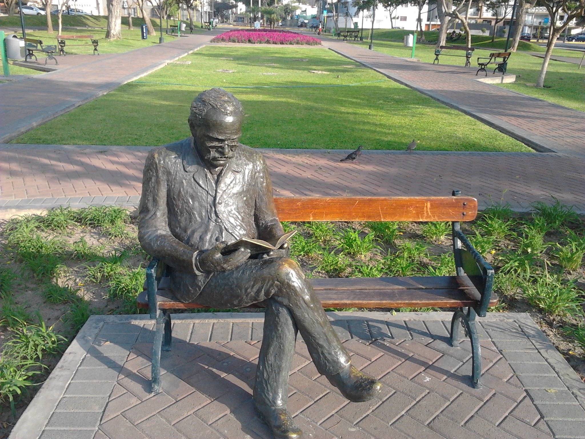 a statue of a man is sitting on a park bench reading