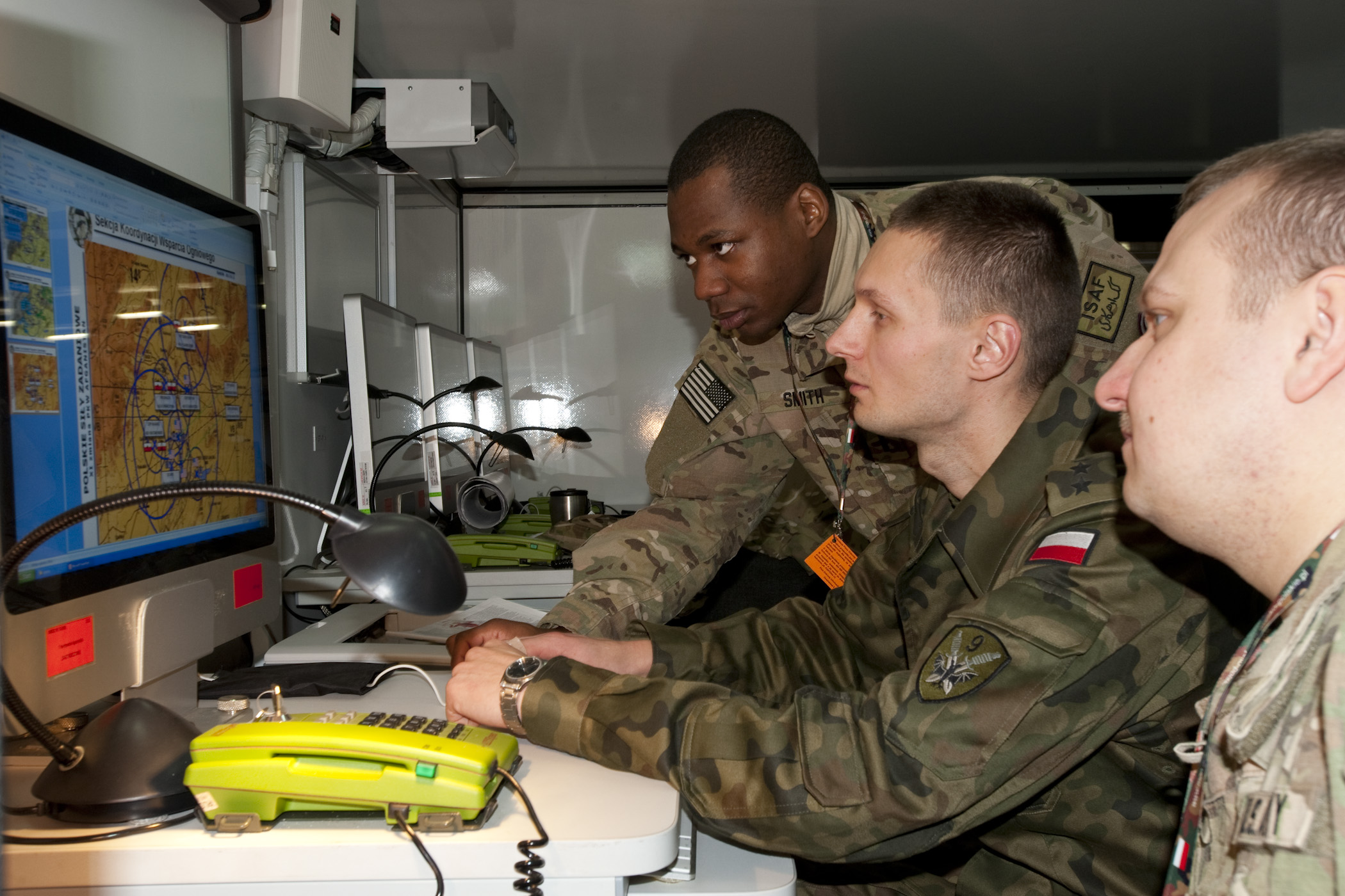 two men wearing camouflage are at a computer