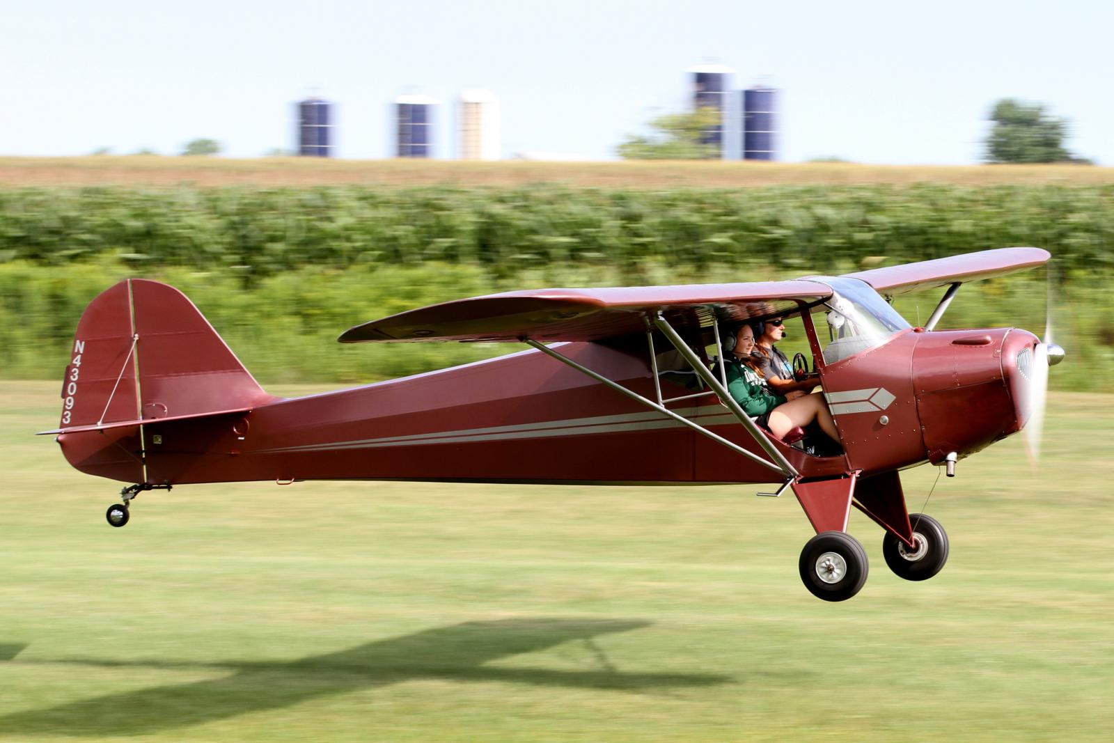 a small red plane with two people sitting in it