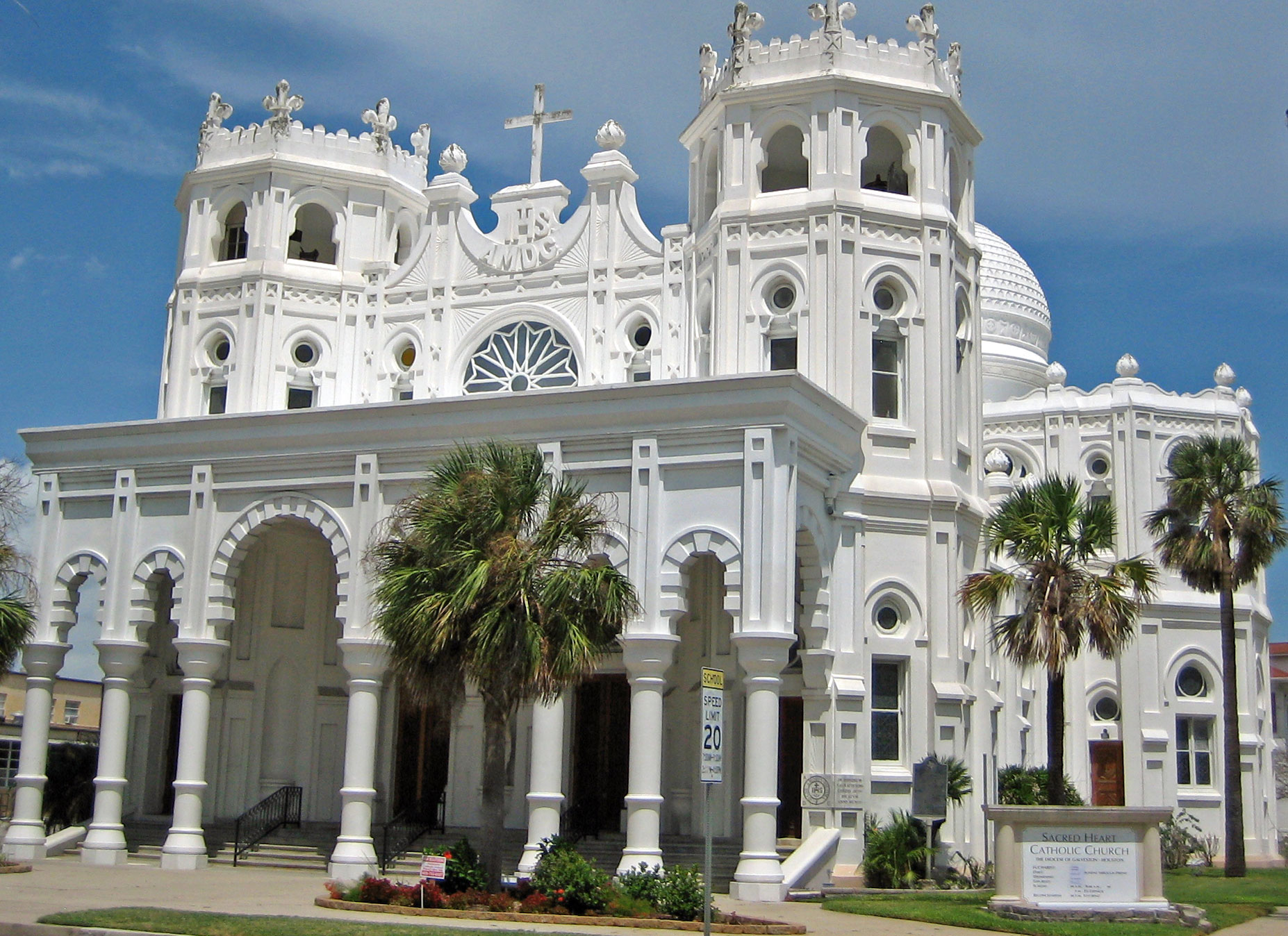 a large white building with a clock and crosses at the top