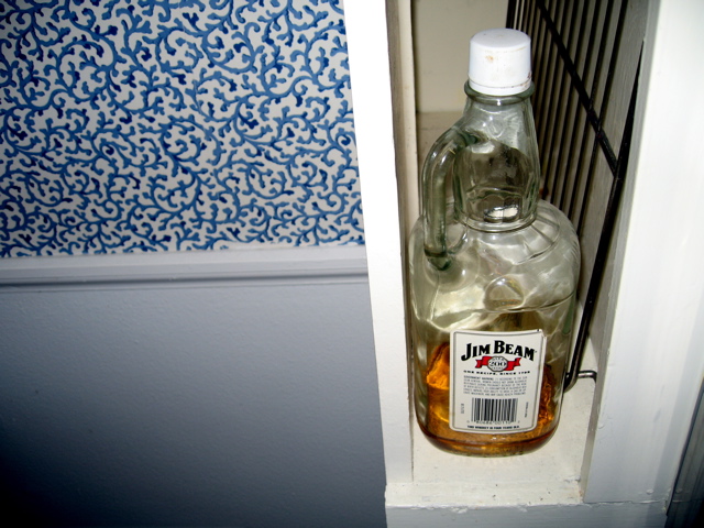 a glass jar filled with liquid next to a wire door