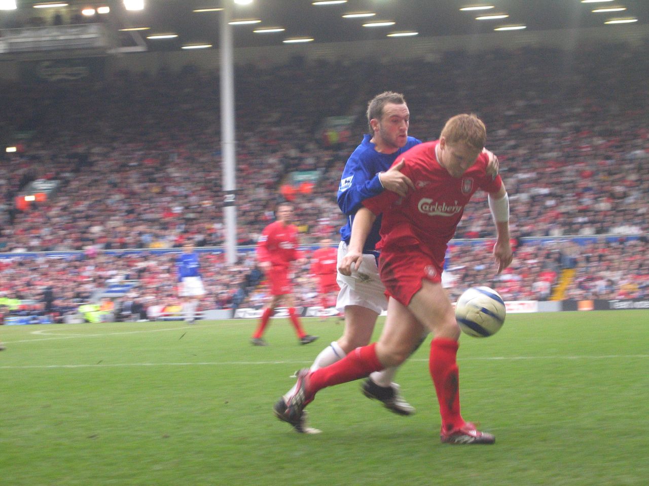 two soccer players in red uniforms kicking the ball