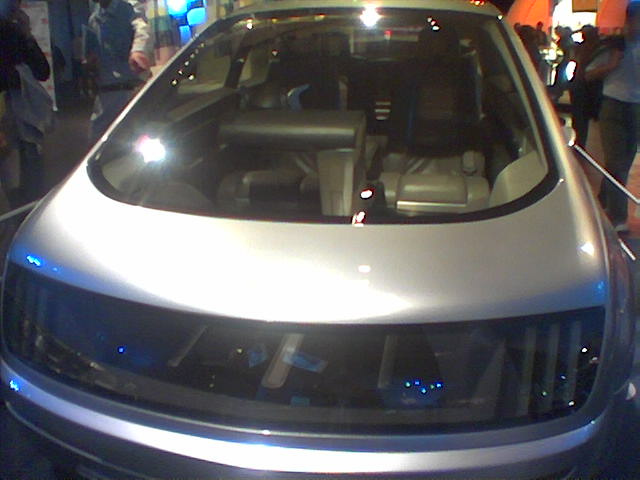 a silver car sitting at an event with its hood up