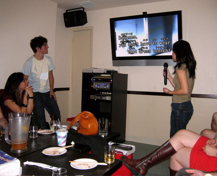group of people standing in front of a tv watching television