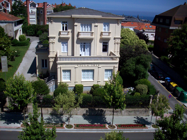 an aerial view of a big mansion next to the ocean