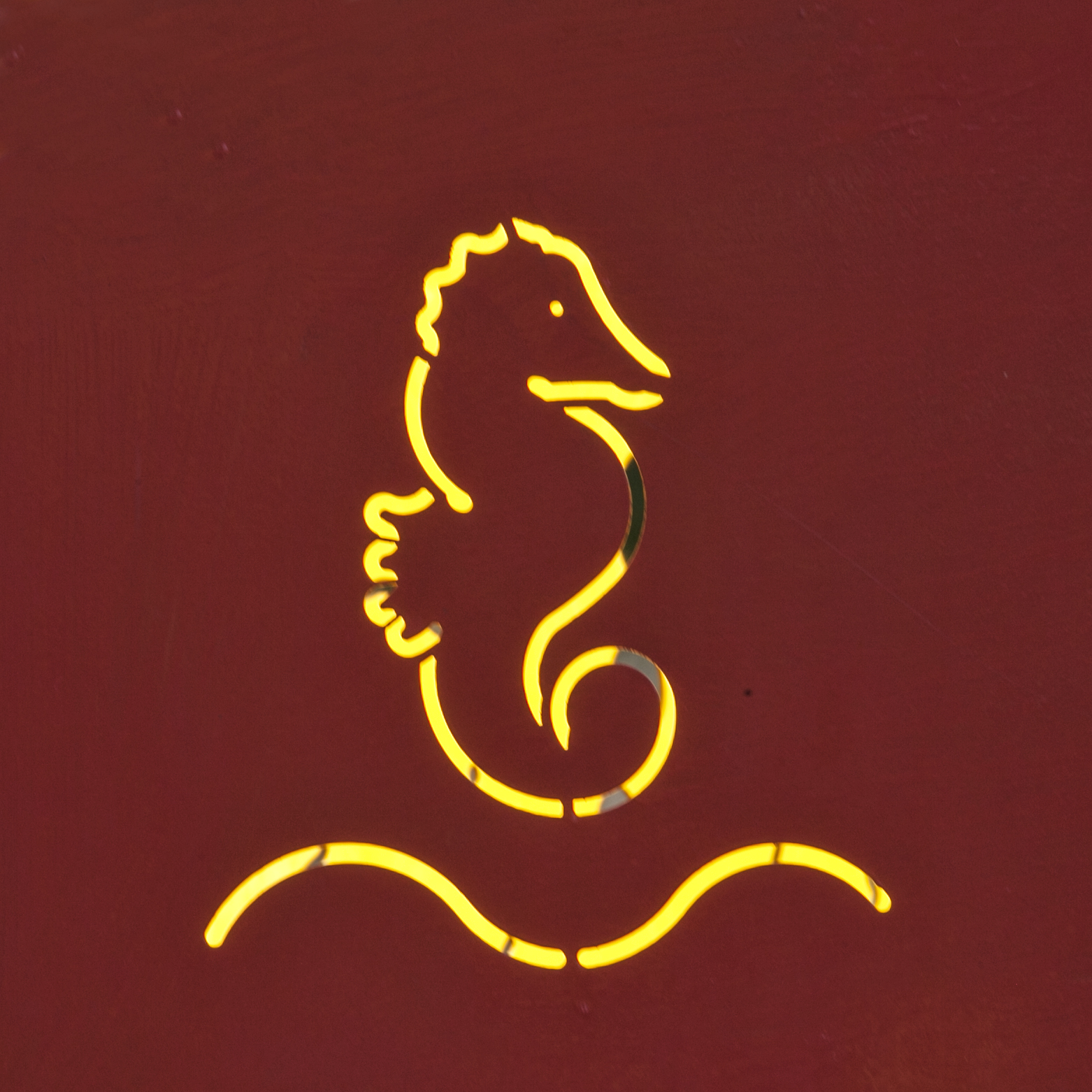 yellow neon seahorse sign on red surface