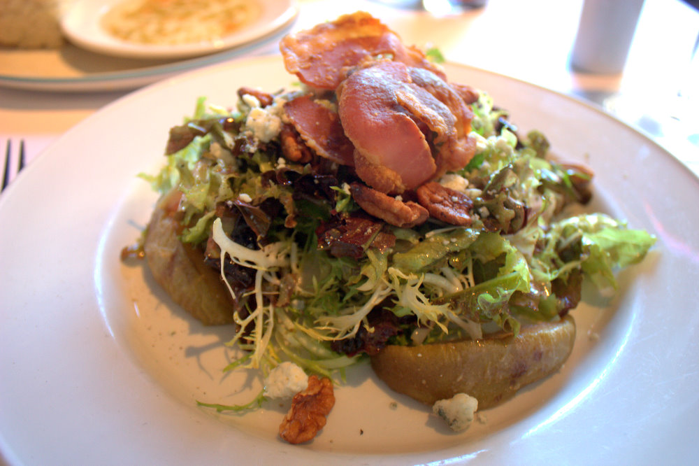 an interesting salad is piled with bacon on the top