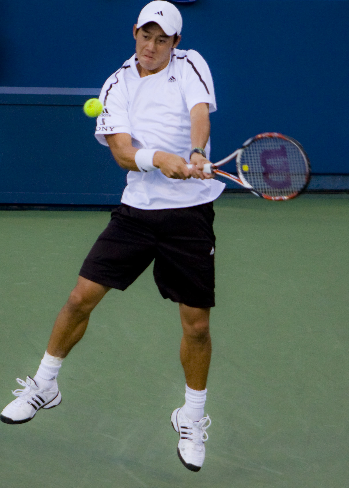 man in black shorts and white shirt playing tennis