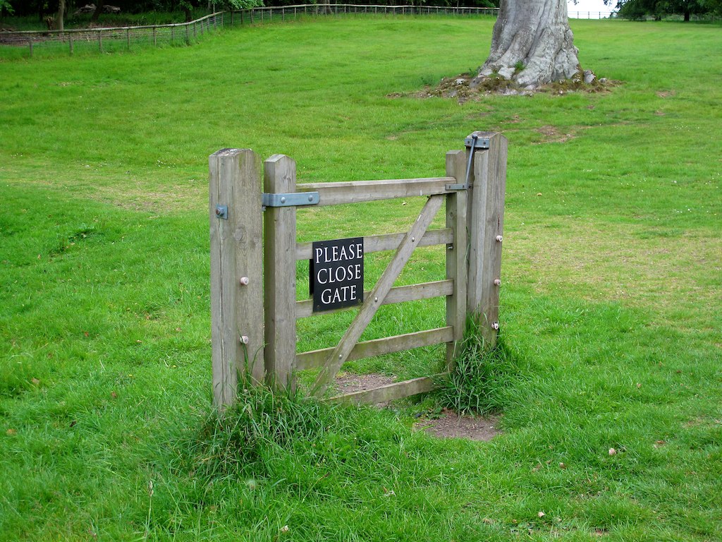 a gated in grassy area with trees behind it
