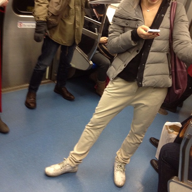 a woman wearing grey pants is looking at her phone