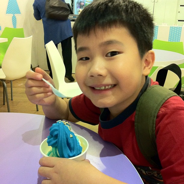 young child eating blue dessert in cafe setting