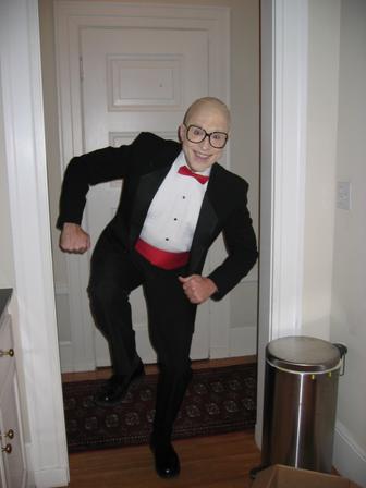 a man dressed up in a tux stands in front of an open door