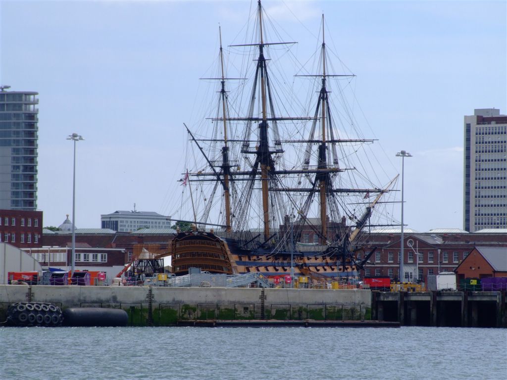 a large ship sits in the water near tall buildings