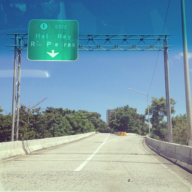 a green highway sign sitting above an empty highway