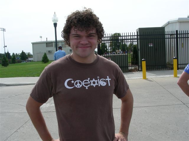 a smiling young man in a t - shirt is outside
