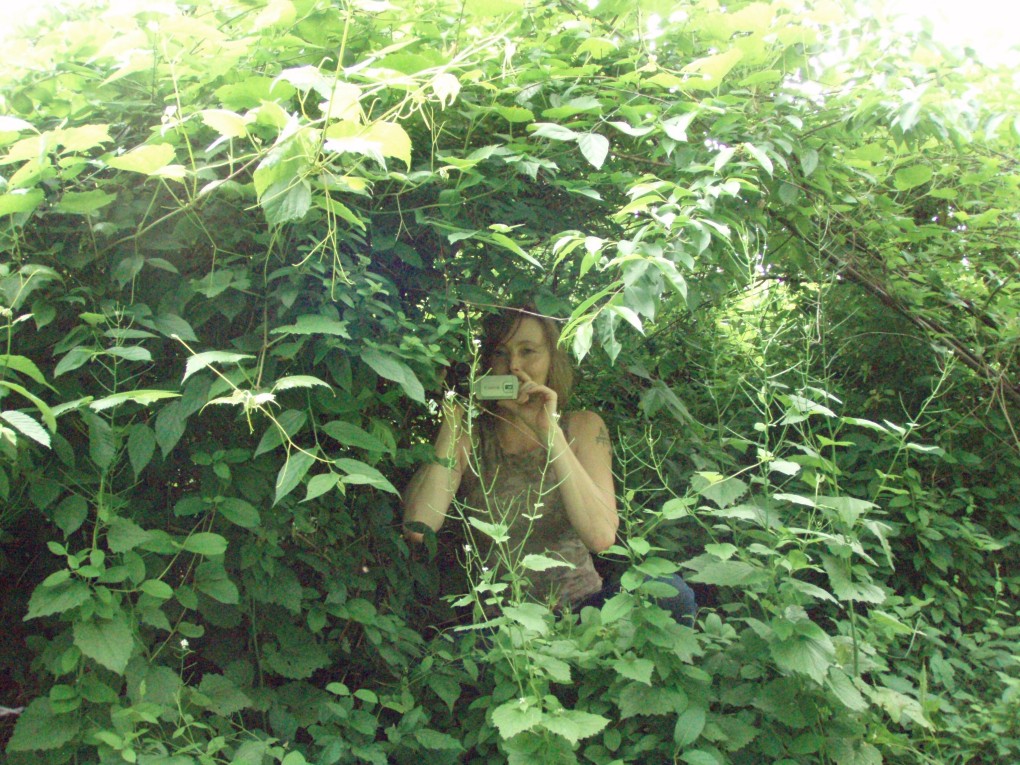 the girl is looking at herself through the foliage