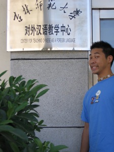 an asian man smiles near the entrance to a business