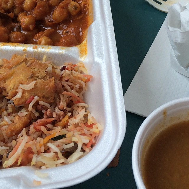 a lunch in a foam container with chicken, beans and rice