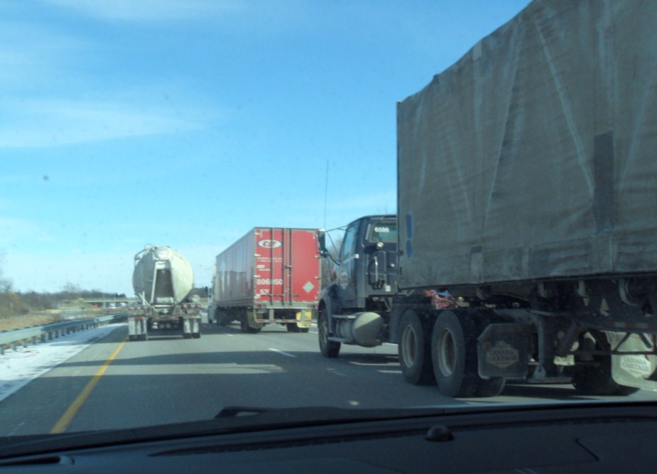 large trucks driving on highway near roadway under clear skies