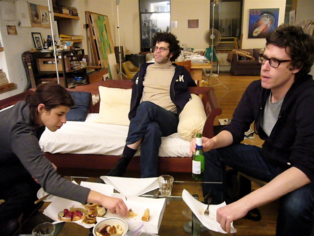 three people are sitting on a couch while eating