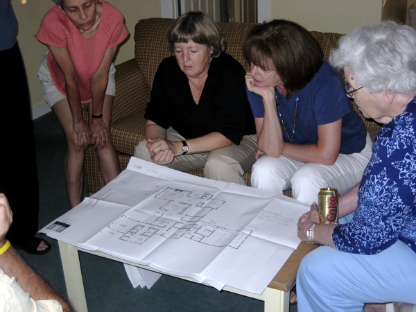 group of people sitting around an architectural design plan