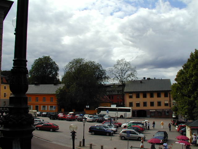 a city square filled with parked cars and people