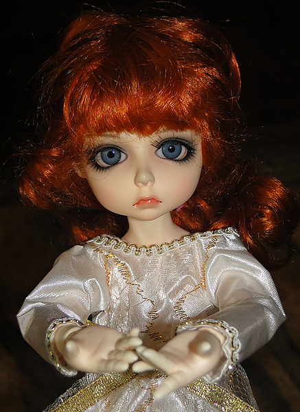 there is a doll wearing a white dress and a golden chain around its arms
