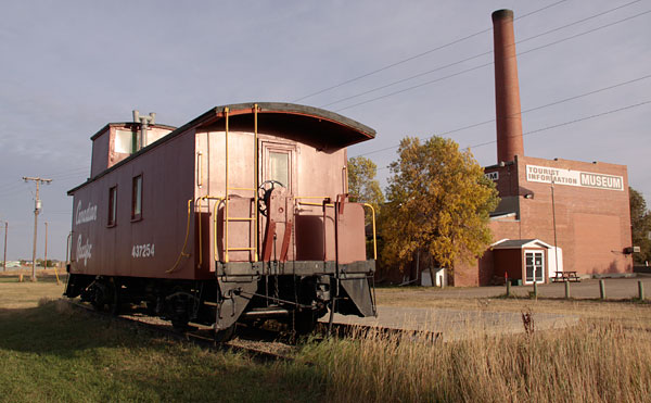 an old train car in front of the factory with no top