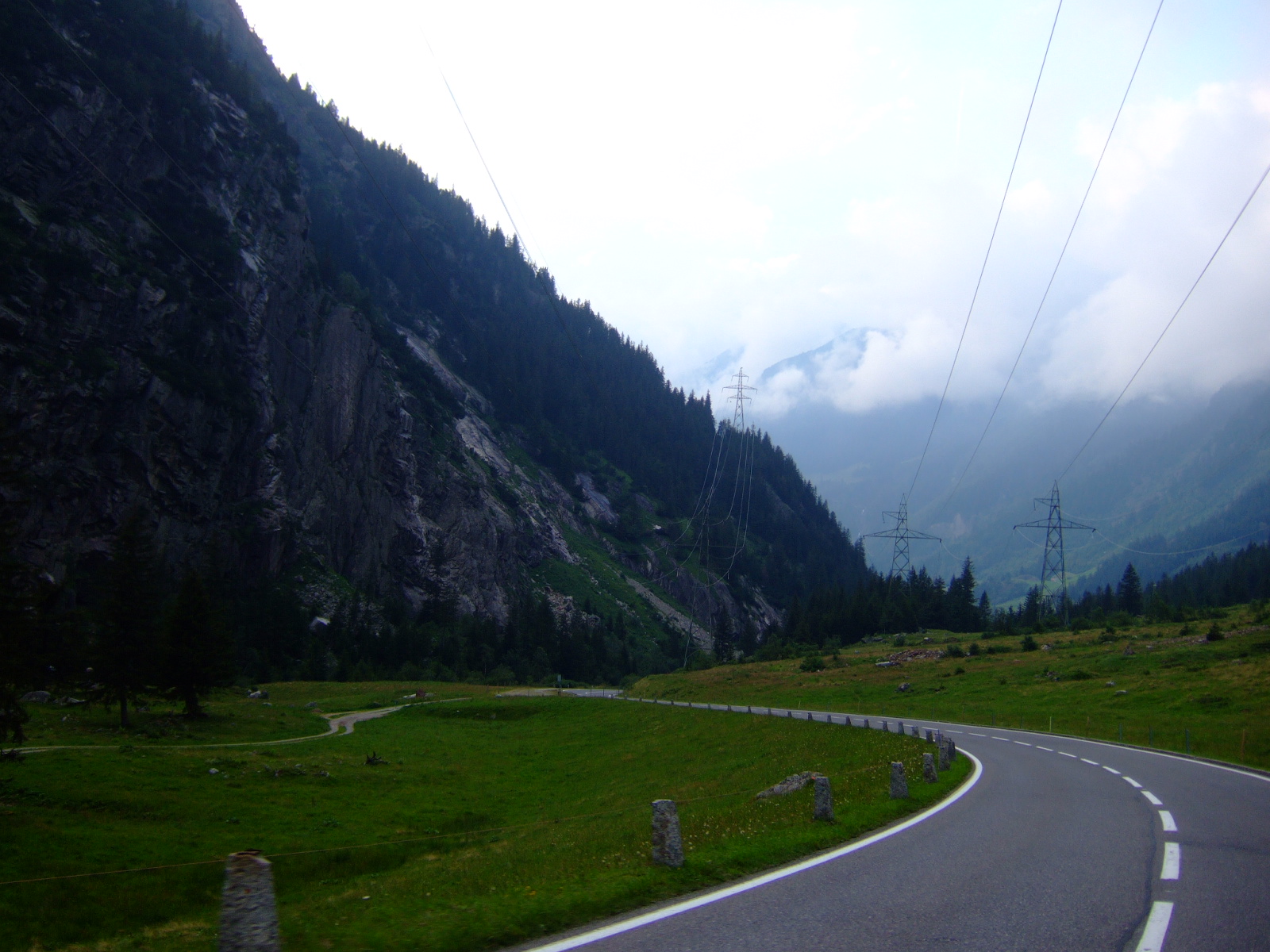 winding highway in green hilly area with power lines