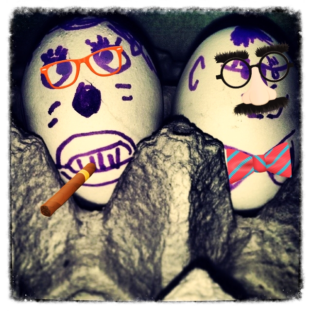 two painted eggs in the shape of heads with a cigarette in their mouths