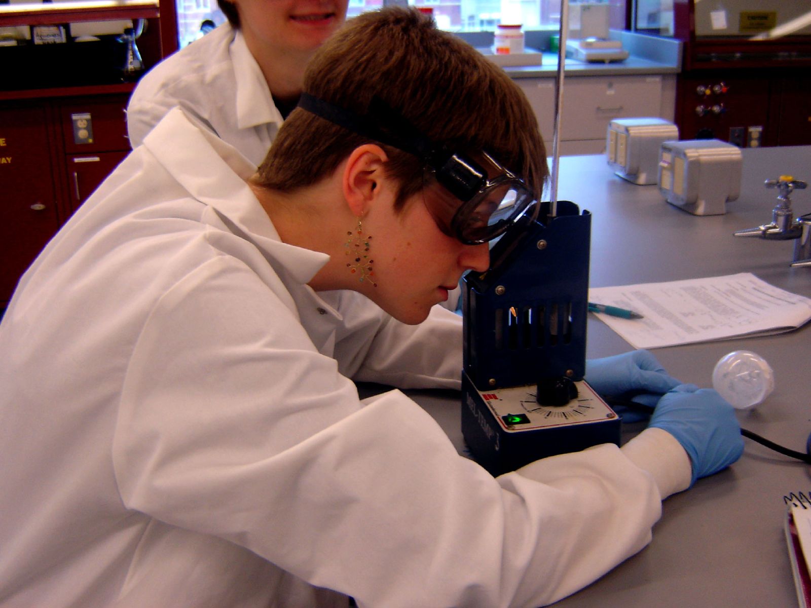 two people in a lab looking through a microscope