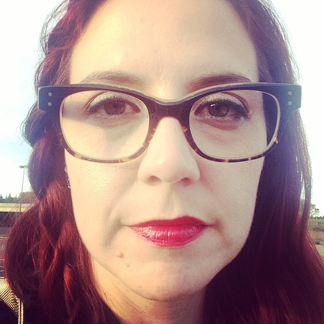 the woman wearing glasses has red hair and big 