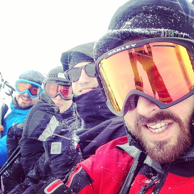 skiers smile and stand together at the top of a slope